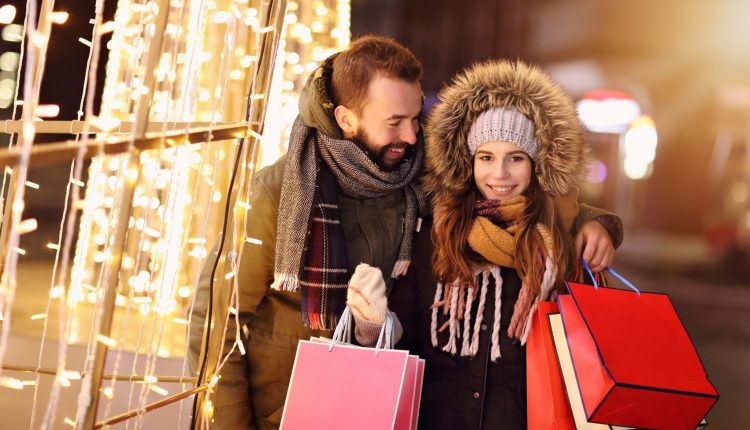 Ein Paar mit Einkaufstüten beim Christmas-Shopping unter Lichterglanz im A6 Fashion Place Herrieden.