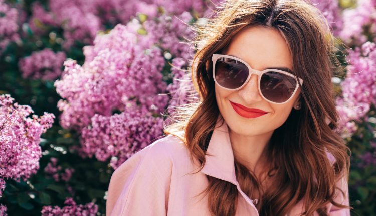 rau mit Sonnenbrille und strahlendem Lächeln in elegantem Frühjahrs-Outfit – festlich, selbstbewusst, bereit für den schönsten Anlass.